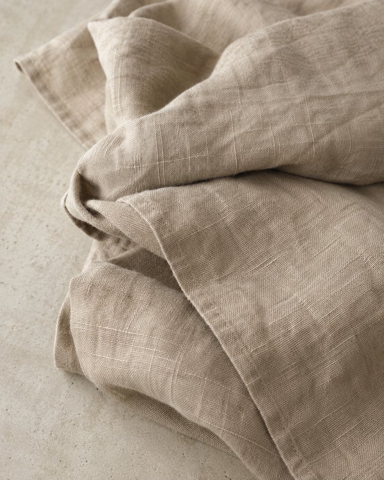 Loosely folded stonewashed linen on a concrete surface, showing the characteristic crinkle of the weave